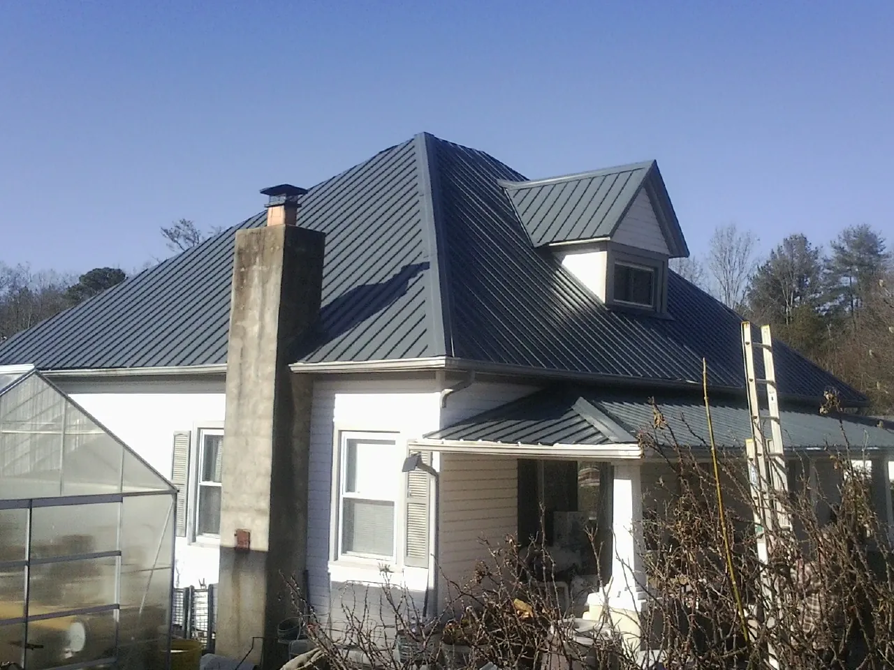 Dark blue standing seam metal roof on a white farmhouse with dormer — Slate & Tile Roof Repair by Roofing Brothers in Exmore