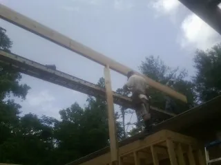 Carpenter setting a ridge beam over a new addition frame — Ice Dam Removal by Roofing Brothers in Exmore