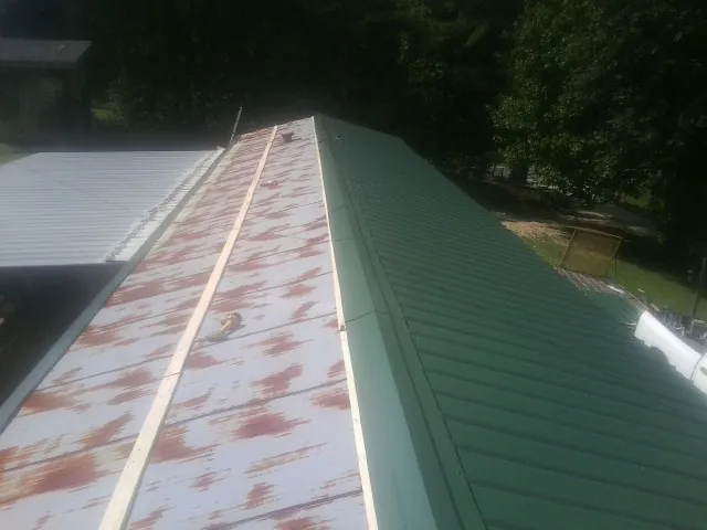 Old rusted panels beside newly installed green metal roofing — Wind Damage Roof Repair by Roofing Brothers in Exmore