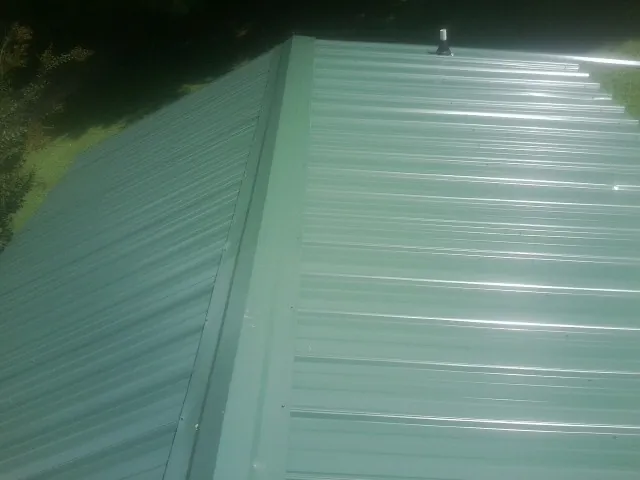 New green metal panels meeting at the ridge of a roof — Flat Roof Repair work by our crew in Exmore