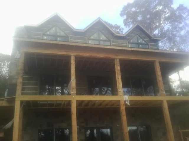 Dormers and porch framing on a large log home under construction — Roof Coating work by our crew in Exmore