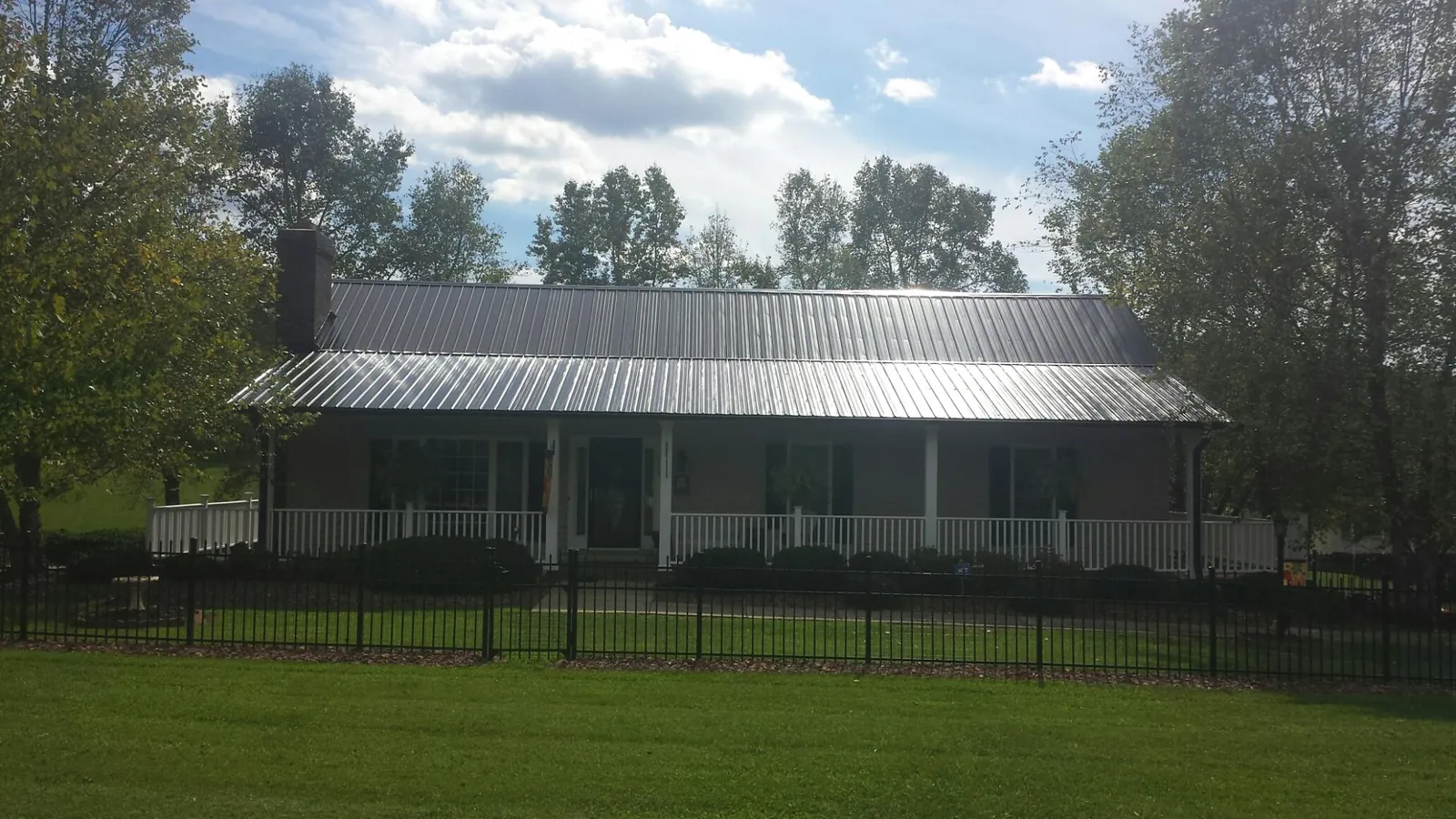 Gray metal roof on a brick ranch with a full width front porch — Gutter Guard Installation work by our crew in Exmore