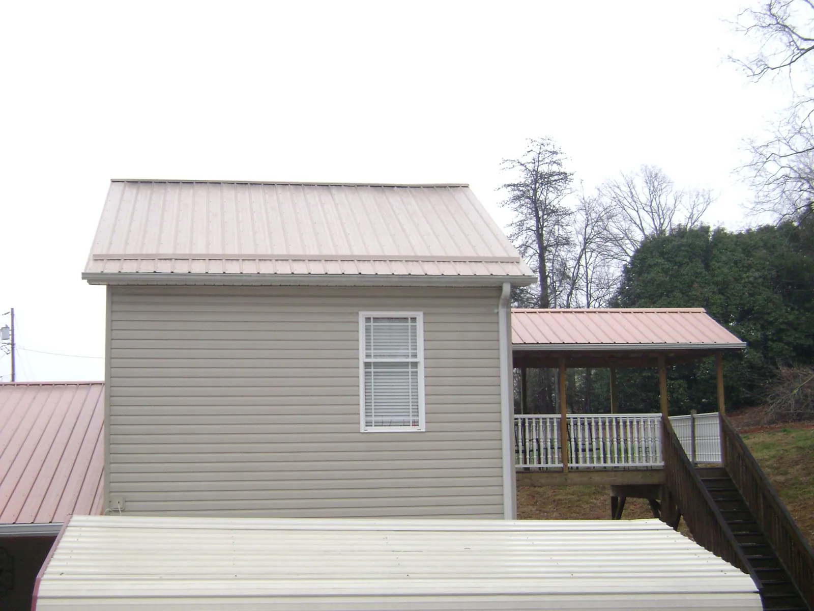 Tan metal roofs on a two story addition and attached porch, from a Roof Replacement job in Exmore