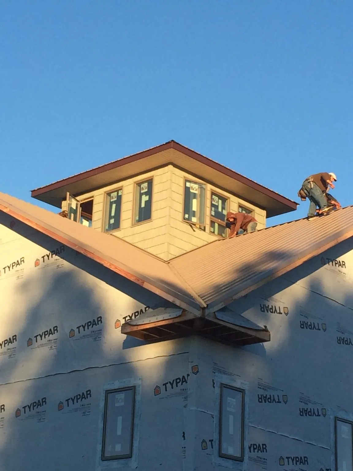 Roofers working around a rooftop cupola on a new metal roof at sunset — Roof Waterproofing in Exmore by Roofing Brothers